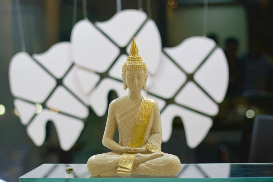 Buddha statue on a glass shelf in front of tooth-shaped lights